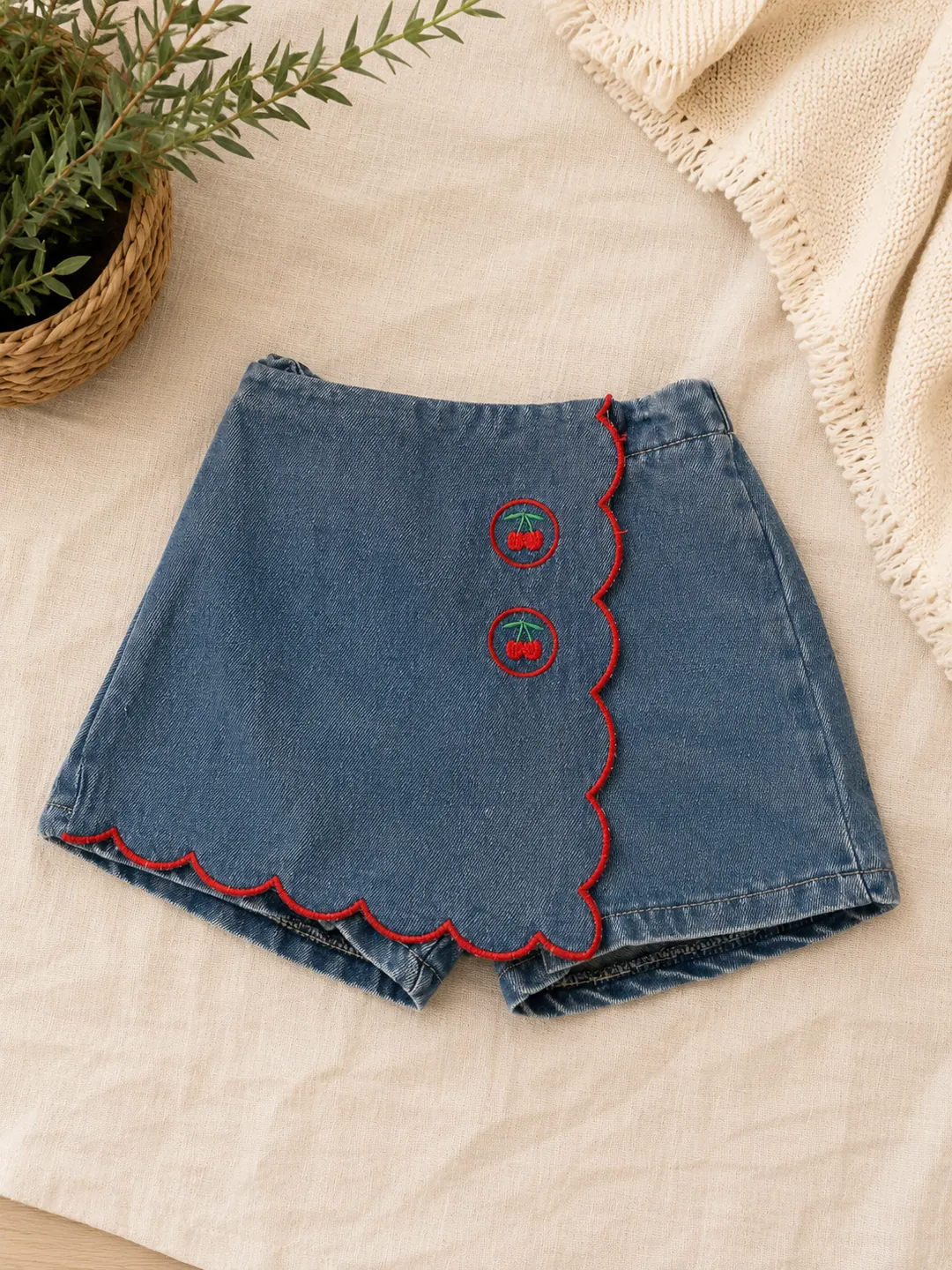 Denim baby skort with red scalloped trim and cherry buttons